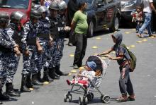 enfant palestinien pousse un bébé devant des soldats isréliens
