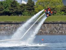 Un japonais s'essaye à des acrobaties sur un Flyboard, propulsé grâce à l'air et à l'eau mais relié 