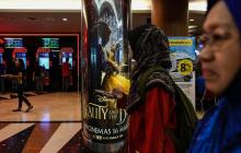 Deux femmes voilées passent devant l'affiche du film "La belle et la bête" dans un centre commercial