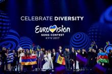 Des chanteurs et chanteuses finalistes du concours de l'Eurovision devant le slogan du concours "Cél