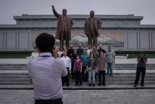 Des touristes posent devant les statues géantes de Kim Il-Sung et Kim Jong-Il, à Pyongyang, le 23 ju