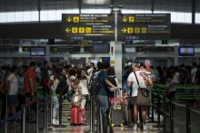 Des passagers font la queue au contrôle de sécurité de l'aéroport de Barcelone, El Prat, le 11 août 