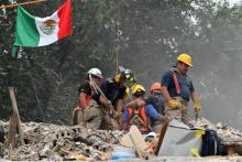 Des pompiers déblaient les gravats d'un immeuble qui s'est effondré lors d'un séisme, le 26 septembr