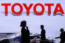 Des visiteurs sur le stand japonais Toyota, près d'une d'une voiture de course Denso Toyota, lors du