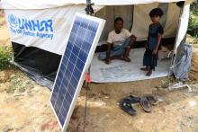 Des réfugiés Rohingyas attendent qu'une lanterne se charge grâce à l'énergie solaire, dans un camp d