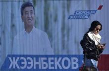 Une femme passe devant une affiche de campagne du candidat à l'élection présidentielle Sooronbai Jee