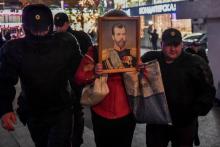 Des policiers arrêtent un manifestant portant un portrait du dernier tsar Nicolas II devant le ciném
