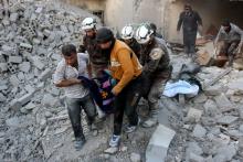 Des "casques blancs" (bénévoles civils) évacuent une victime des décombres d'un immeuble détruit par