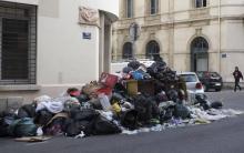 Des sacs poubelles entassés à côté un conteneur à ordures débordant lors d'une grève des éboueurs, l