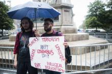 Deux manifestants protestent lundi au pied de la statue de Christophe Colomb à New York, contre le "