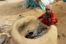 Une petite fille yéménite qui a fui la guerre dans la région de Harad, fait bouillir de l'eau dans u