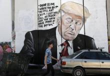 Un homme passe devant un dessin du président américain Donald Trump sur la barriere de sécurité isra