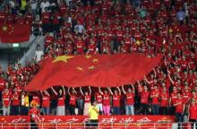 Des supporters chinois brandissent le drapeau pendant l'hymne national, à un match de football