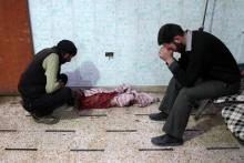 Deux hommes désespérés face au corps sans vie d'un enfant tué par des bombardements du régime syrien
