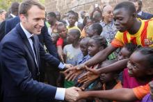 Emmanuel Macron serrant les mains d'enfants burkinabés, après la visite d'une école de Ouagadougou, 