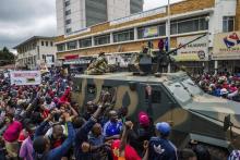 Des manifestants au côté d'un transport de troupes de l'armée zibabwéenne le 18 novembre 2017 lors d