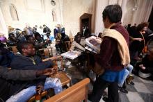 Des bénévoles distribuent de la nourriture à des migrants dans l'église Saint-Ferréol de Marseille l