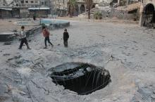 Des enfants marchent près d'un cratère causé par une frappe aérienne à Douma, ville syrienne à l'est