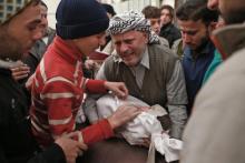 Un Syrien et son fils pleurent une petite fille tuée par un bombardement aérien sur une localité reb