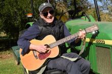 Le musicien américain Daniel Antopolsky joue de la guitare sur un tracteur à Fargues-Saint-Hilaire, 