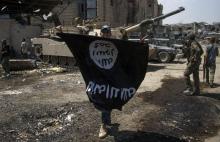 Un membre des troupes d'élite irakiennes brandit un drapeau retourné de l'Etat islamique, le 1er jui