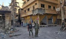 Des forces du régime syrien font le V de la victoire au milieu des destructions dans la ville de Dei
