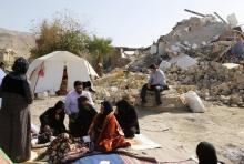 Des Iraniens assis devant leurs maisons en ruine après le séisme ayant frappé l'ouest de l'Iran, le 