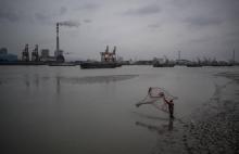 Pêcheur le 21 février 2017 dans la rivière Huangpu, face à la centrale électrique à charbon de Wujin