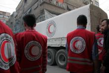 Des membres de la Croix-Rouge syrienne s'apprêtent à décharger des camions transportant des cartons 