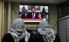 Deux palestiniens regardent le président américain Donald Trump reconnaître officielement Jérusalem 
