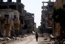 Un membre des Forces démocratiques syriennes marche dans une rue détruite de l'ancienne "capitale" d