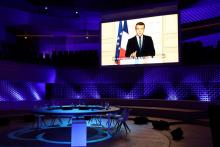 Un discours d'Emmanuel Macron est diffusé sur des écrans avant l'ouverture d'un sommet sur le climat