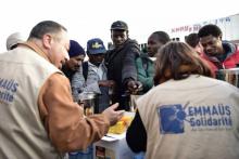 Des membres de l'association Emmaüs distribuent des vivres à des migrants dans un campement Porte de