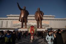 Des Nord-Coréens s'éloignent des statues des leaders défunts Kim Il-Sung (g) et Kim Jong-Il (d) aprè