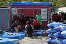 Jose Figueroa (à droite) nettoie kayaks de location et équipements en attendant le retour des touris