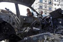 Des garçons yémenites regardent à l'intérieur d'une voiture brûlée lors des combats entre rebelles e