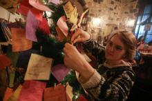 Une jeune Syrienne épingle un voeu sur l'arbre de Noël du café Zeriab à Damas