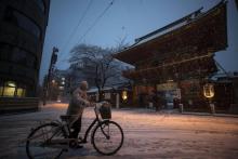 Un homme marche à côté de son vélo le 22 janvier 2018, à Tokyo, où l'agence météorologique du Japon a émis sa première alerte aux chutes de neige depuis quatre ans