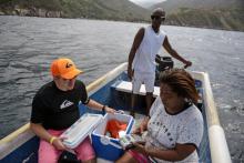 Nancy Rodriguez (d), à bord d'une barque pour capter un réseau téléphonique, sort son terminal de paiement pour facturer un touriste, le 13 janvier 2018 à Chichiriviche de la Costa, à 70 km de Caracas