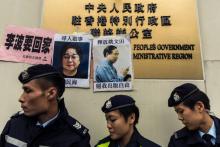 Des policiers passent le 3 janvier 2016 devant des avis de recherche concernant l'éditeur-libraire Gui Minhai (G), de la maison d'édition basée à Hong Kong "Mighty Current", et son collègue Yau Wentia