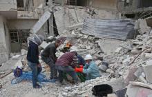 Des secouristes retirent des décombres un corps après des bombardements du régime contre la localité de Hazeh dans l'enclave rebelle de la Ghouta orientale, le 26 février 2018