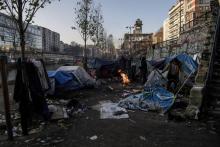 Des migrants notamment d'Afghanistan se réchauffent autour d'un feu de camp à Paris le long du Canal St Martin, le 23 février 2018
