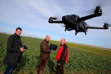 L'agriculteur français Cédric Jullien (D), Emeric Oudin, directeur général d'Axe Environnement (C) et un pilote de drone font voler l'appareil au-dessus du champ de l'agriculteur, à Semoine, dans l'Au