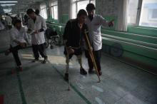 Un médecin afghan soutient un homme amputé, dans un Centre de la Croix-Rouge à Kaboul le 13 février 2018
