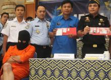 Un Allemand arrêté en possession de drogues à l'aéroport de Bali est présenté aux médias, le visage masqué, à Denpasar le 22 février 2018