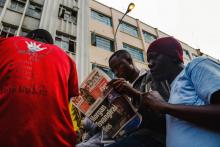 Des Zimbabwéens lisent le journal après la mort de Morgan Tsvangirai, la figure historique de l'opposition dans le pays, le 15 février 2018 à Harare.