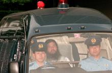 Le 19 juillet 1995, Shoko Asahara (c), gourou de la secte Aum, est escorté par la police jusqu'à un tribunal à Tokyo