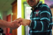 Un pensionnaire de la maison de retraite Lou Cigalou, atteint d'un handicap mental, tient la main d'un aidant, le 13 mars 2018