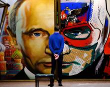 Un homme examine une peinture du président russe Vladimir Poutine le présentant en "SuperPoutine" dans une exposition à Moscou, le 6 décembre 2017