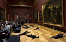 Des militants de la cause climatique allongés devant "Le Radeau de la méduse" le 12 mars 2018 au Louvre à Paris